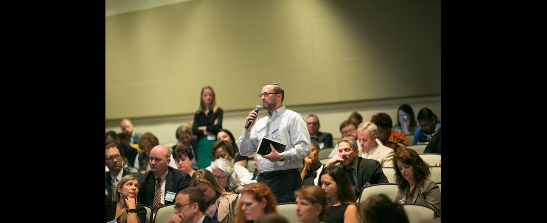 Man speaking from audience with microphone at conference